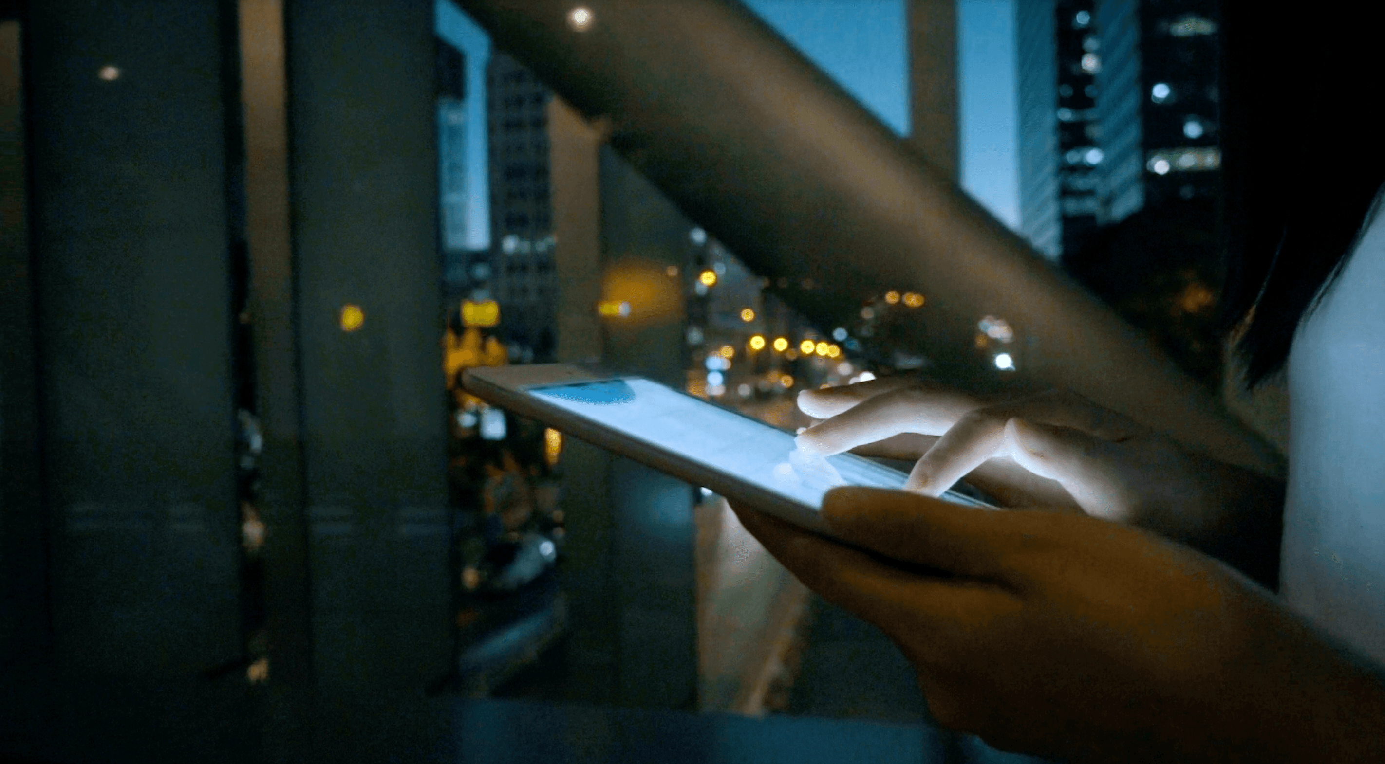 Moderne Stadtansicht im Hintergrund, eine Person läuft auf ihrem Tablet wischend vorbei.
